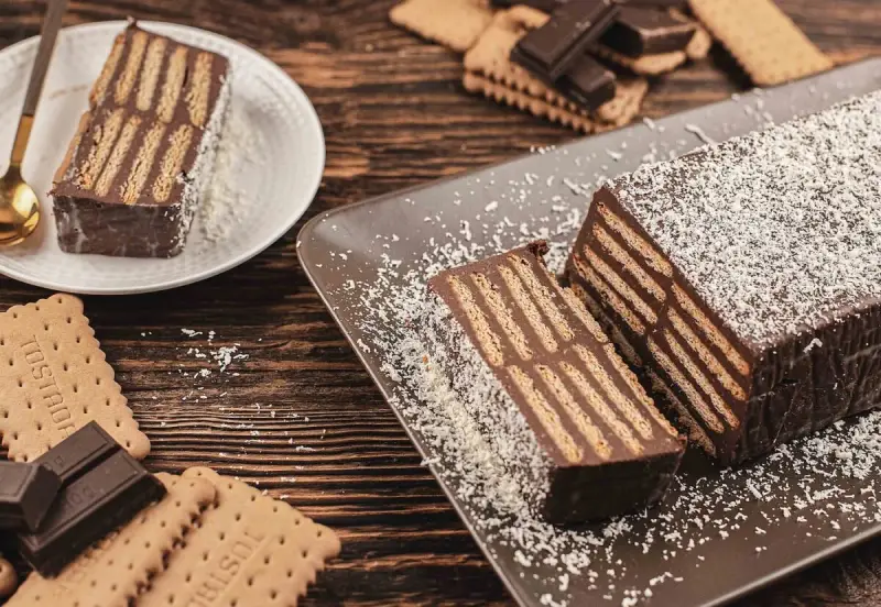 Tarta de chocolate y galletas, un postre casero con capas de galletas y crema de chocolate, espolvoreada con coco rallado.